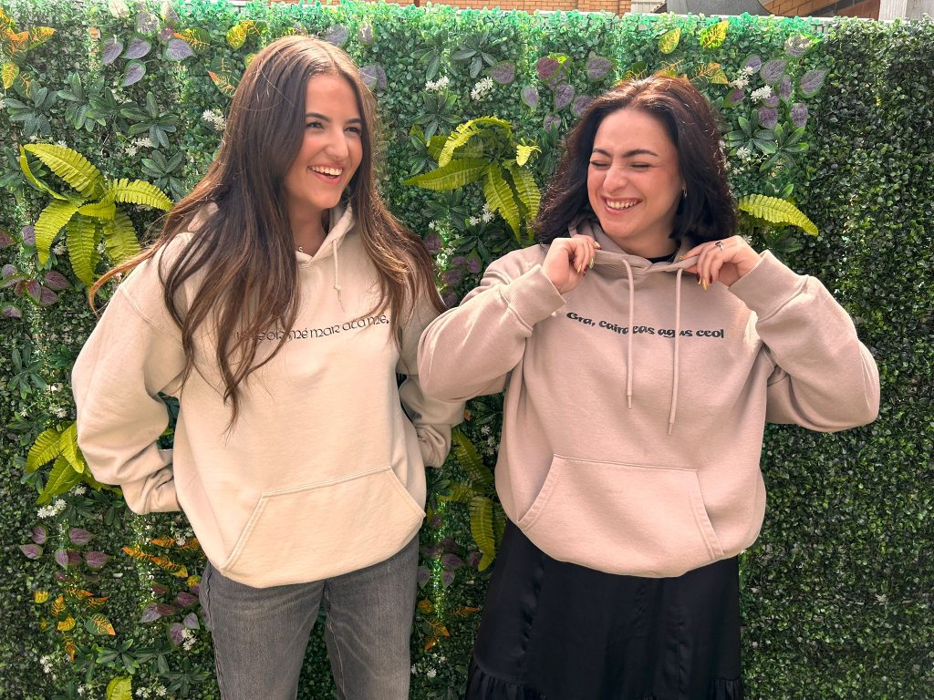 Two people smiling in Grá Duit hoodies